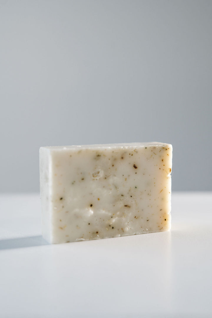 Bar of soap on a white surface with a gray background.