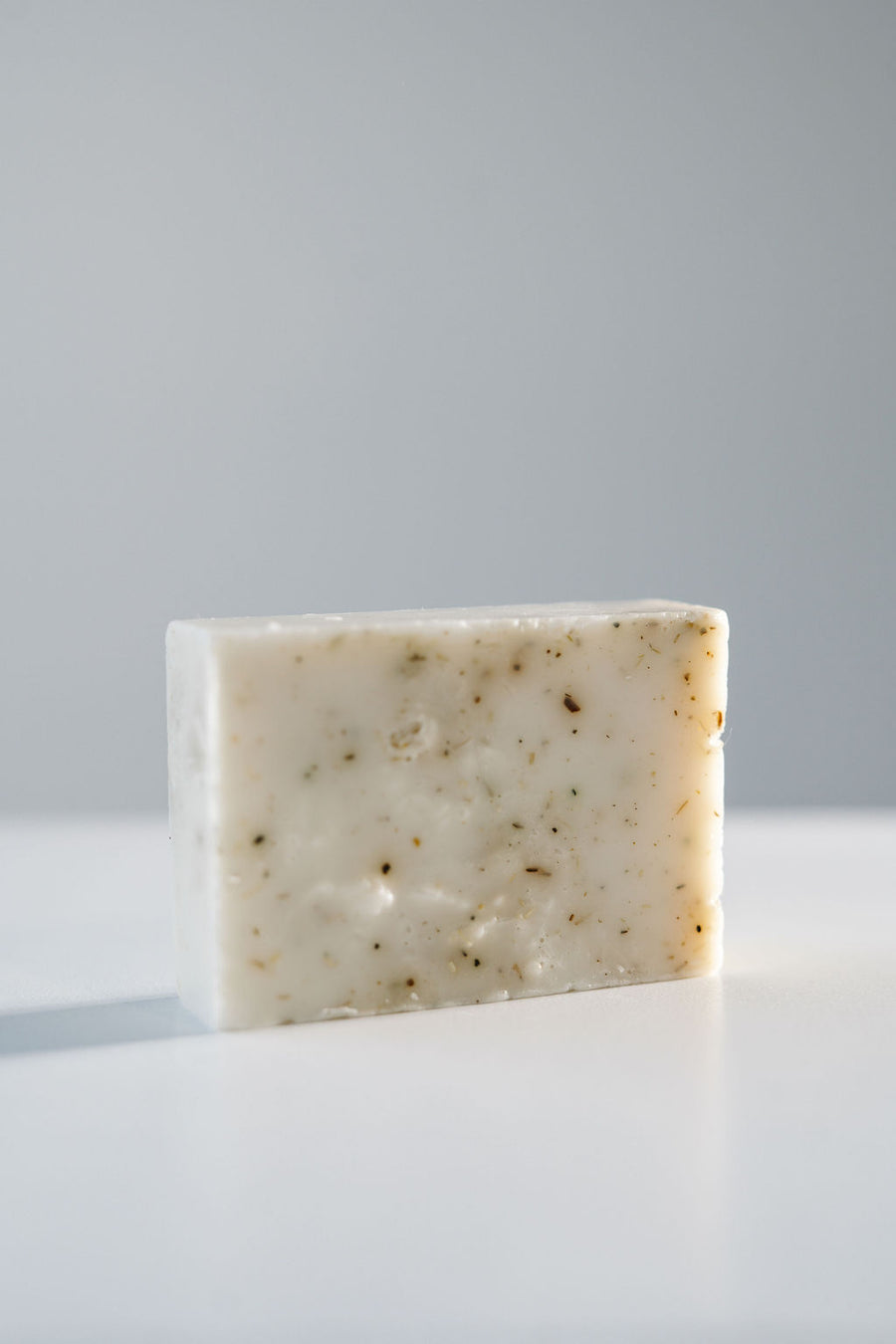 Bar of soap on a white surface with a gray background.