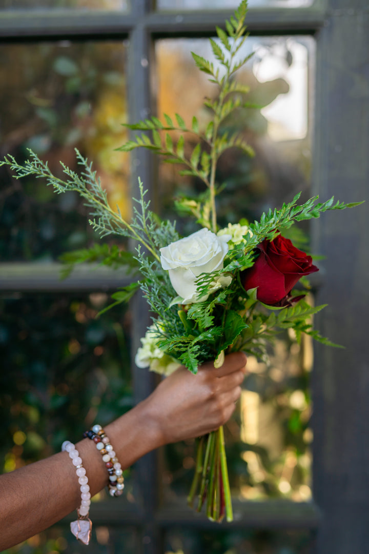 Hand holding a bouquet of flowers with a blurred background