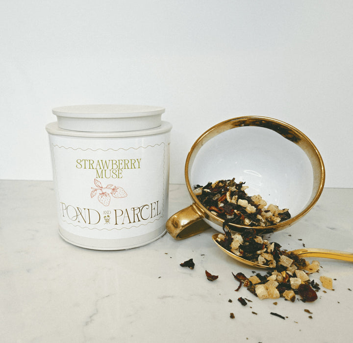 Tea canister labeled 'Strawberry Muse' with a scoop of tea leaves.